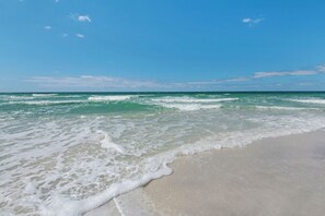 A beach with waves approaching the shore under a clear sky. - 1st Floor Gulf Side- Lagoon Pool- Beach Chair Setup (Panama City Beach)