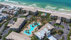 A resort with a swimming pool, beachfront, and multiple buildings. - 1st Floor Gulf Side- Lagoon Pool- Beach Chair Setup (Panama City Beach)