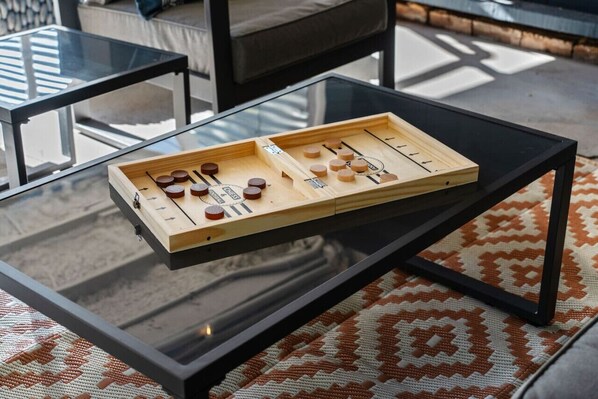 Een houten bordspel op een glazen tafel, met een patroonrijk vloerkleed eronder.