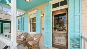 A porch with wicker chairs and a door with blue shutters. - Walk to the Beach, Historic Cottage  (Galveston)