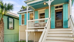 A two-story house with a porch and a staircase leading to the front door. - Walk to the Beach, Historic Cottage  (Galveston)
