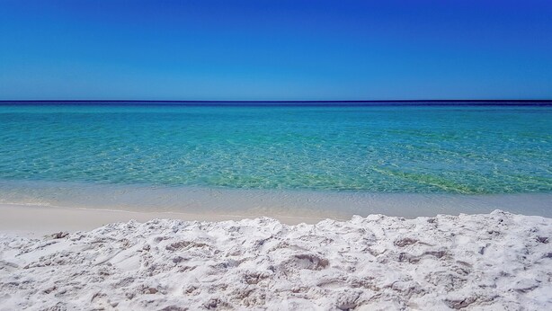 Uma praia com águas turquesa cristalinas e areia branca.