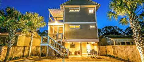 Une maison à deux étages avec une piscine, un patio couvert et une clôture en bois.