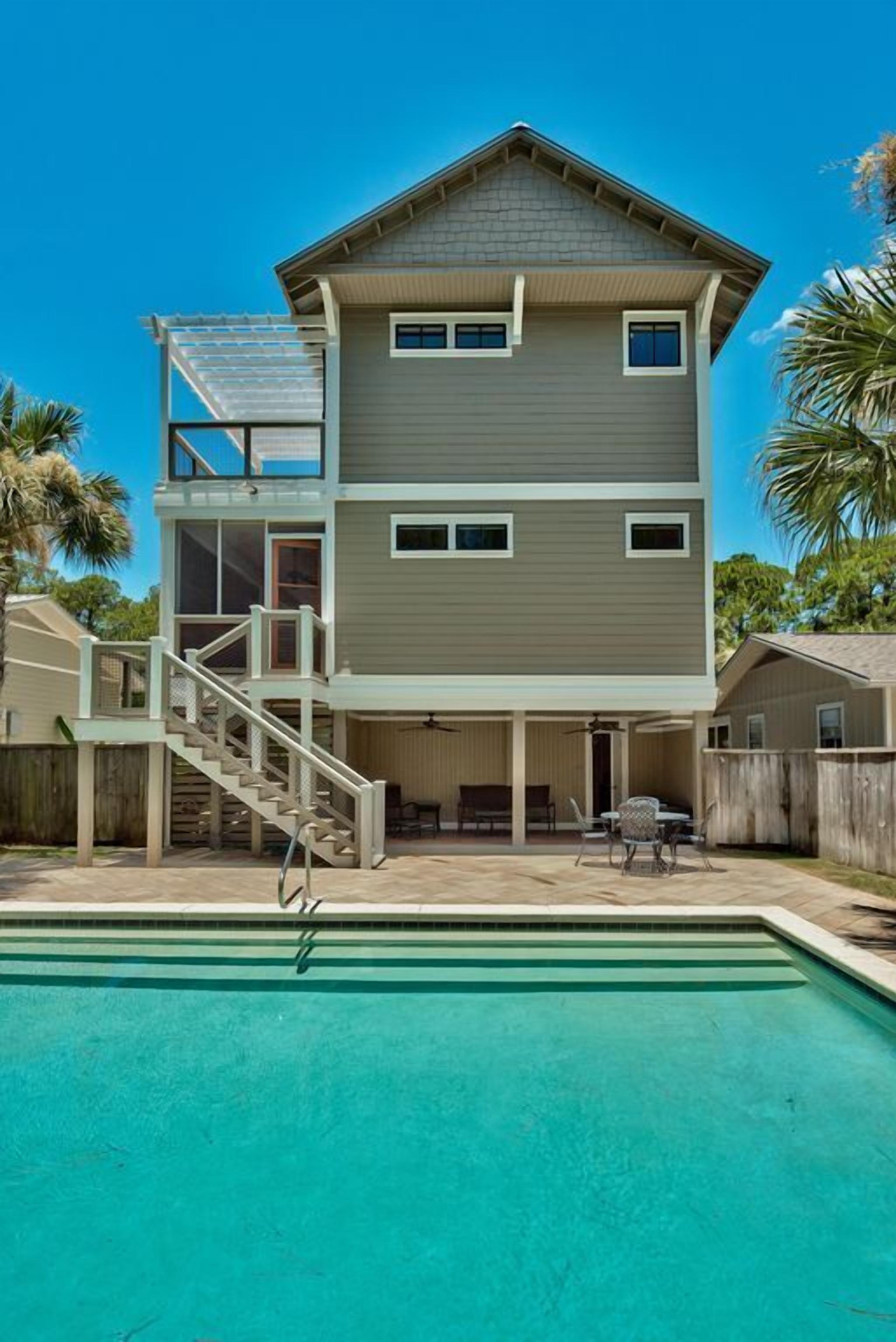 A two-story house with a swimming pool, a covered patio, and a staircase leading to an upper deck.