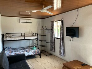 Cozy room with a bunk bed, single bed, and sofa, featuring a flat-screen TV and ceiling fan.