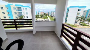 A balcony with a view of multi-story buildings, a tiled floor, and a wooden railing. - Relaxing II, Punta Cana near beaches ✅ (Punta Cana)