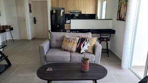 A modern living room with a grey sofa, a dark coffee table, and a small potted orchid. - Relaxing II, Punta Cana near beaches ✅ (Punta Cana)