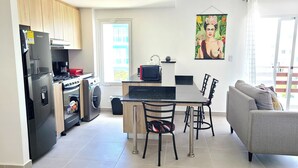 A modern kitchen with a refrigerator, oven, and microwave. There is a dining area with a table and chairs, and a sofa in the living room. - Relaxing II, Punta Cana near beaches ✅ (Punta Cana)