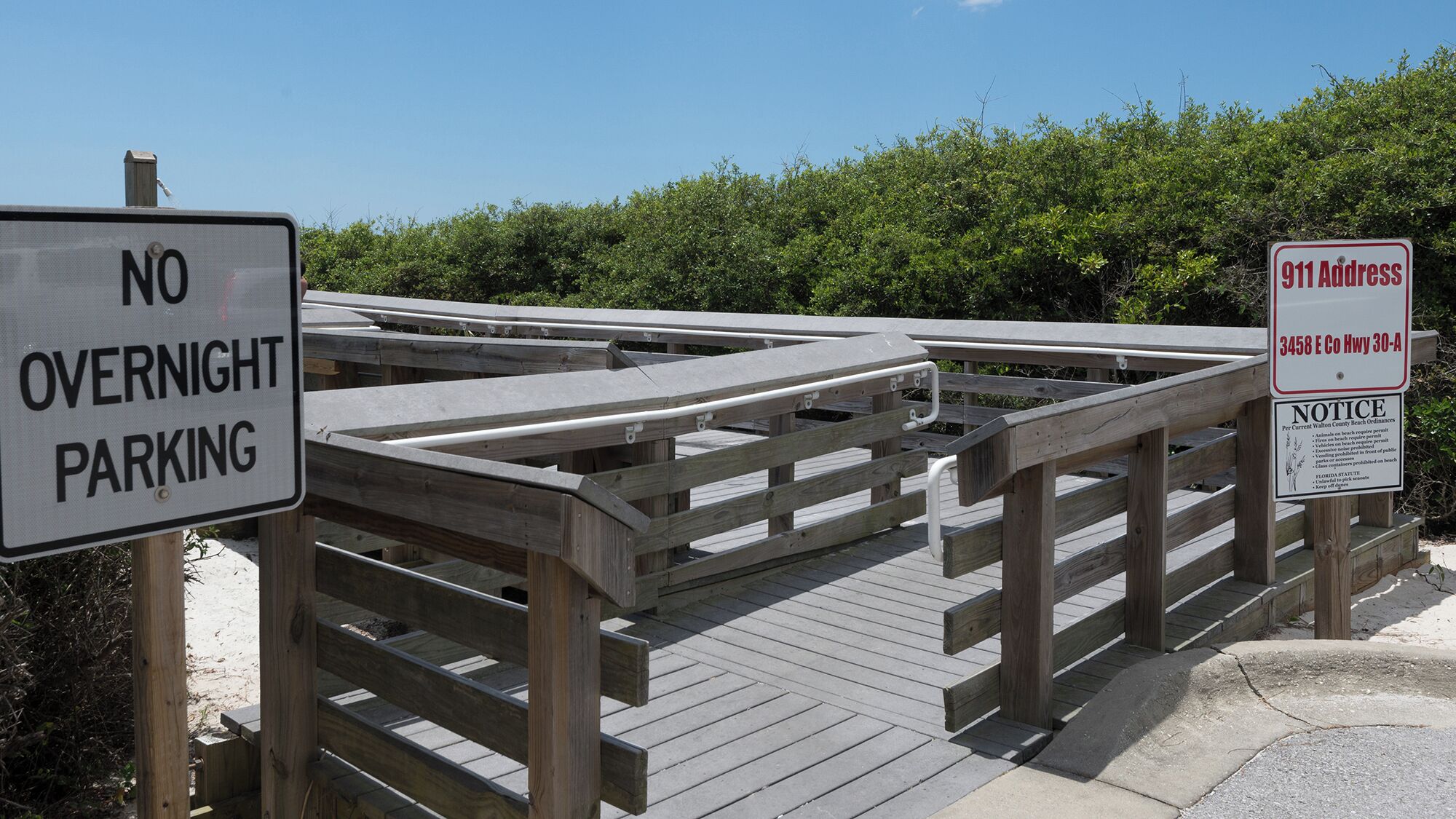 A wooden boardwalk with a 'NO OVERNIGHT PARKING' sign and an '911 Address' sign.