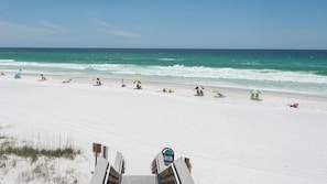 Een strand met wit zand, golven en strandparasols.