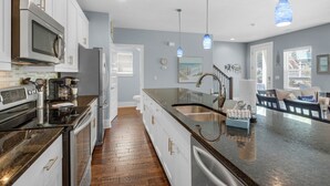 A modern kitchen with stainless steel appliances, a wooden floor, and a large island with a sink. - Blue Mountain Beach - Sleeps 12 - Steps From Pool (Santa Rosa Beach)