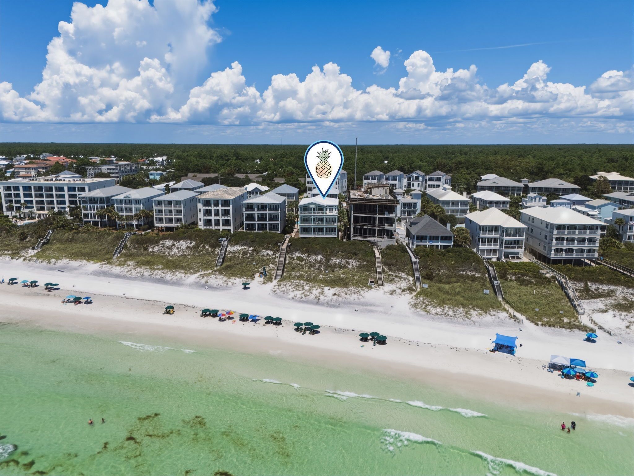 A coastal hotel with multiple buildings, a beach, and a clear sky.
