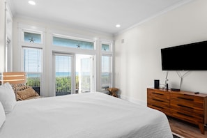 Une chambre avec un grand lit, une commode en bois, une télévision et un balcon décoré d’étoiles de mer.