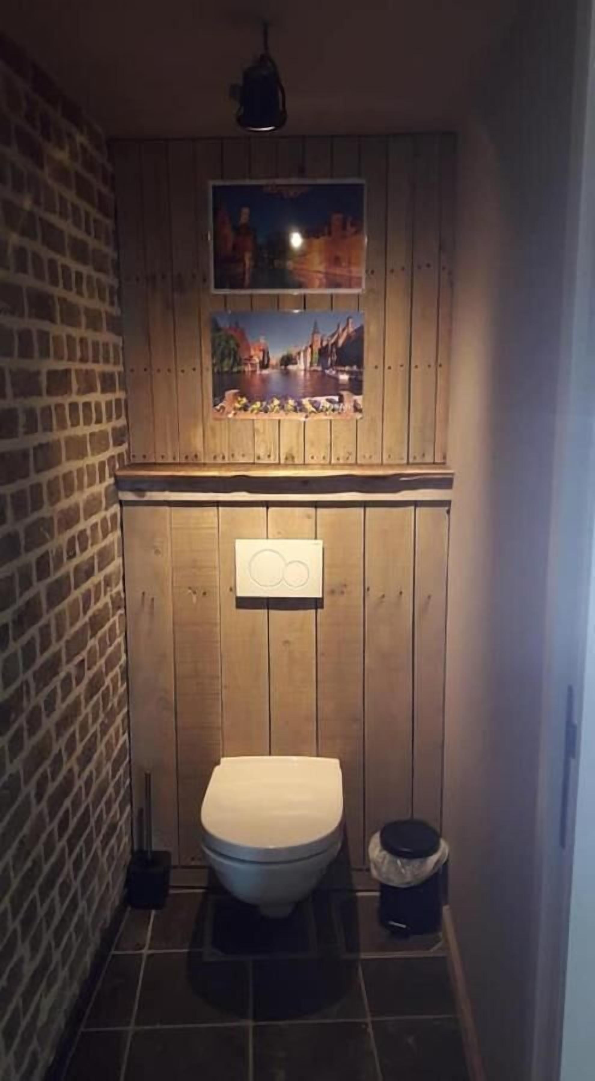 Une petite salle de bain compacte, avec un meuble-lavabo en bois, des toilettes et une poubelle.