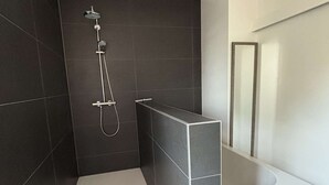 A modern bathroom with a walk-in shower, a standalone bathtub, and a large mirror.