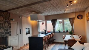 A cozy kitchen with a central island, bar stools, a dining table, and a sofa.