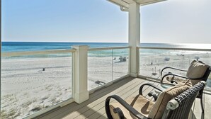 Une terrasse couverte avec vue sur la plage, comprenant une chaise longue et une table.