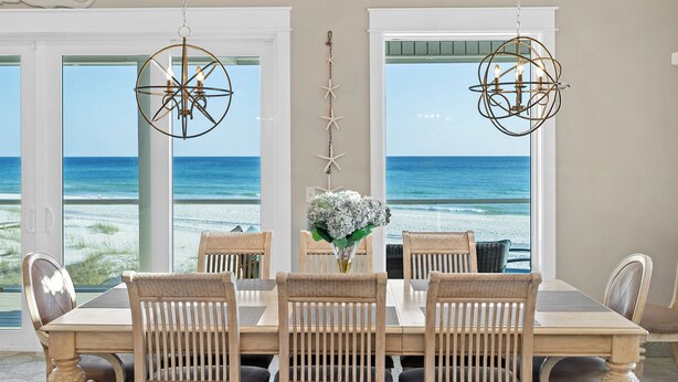 Un coin repas avec une table et des chaises, un vase rempli de fleurs et des décorations en forme d’étoiles de mer.
