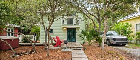 A green house with a porch, a red chair, and a mailbox.