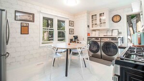 A kitchen with a dining table, chairs, a refrigerator, a washing machine, and a stove. - Walking distance to Old town with Hot tub (Niagara-on-the-Lake)