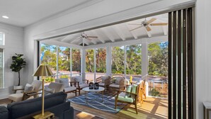 A spacious room with a large sliding glass door leading to an outdoor patio area. Inside, there is a sofa, a coffee table, and several chairs.