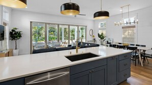 A modern kitchen with a large island, dark cabinetry, and pendant lighting.