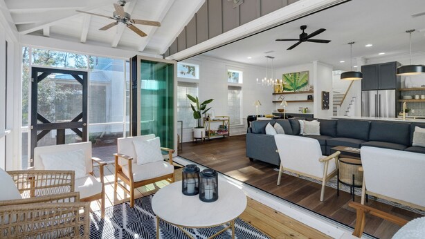 A modern open-plan living area with a sofa, chairs, a dining table, and a kitchen in the background.