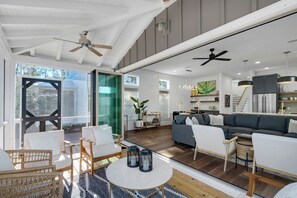 Uma sala de estar espaçosa com um sofá grande, uma mesa de jantar e uma cozinha ao fundo.