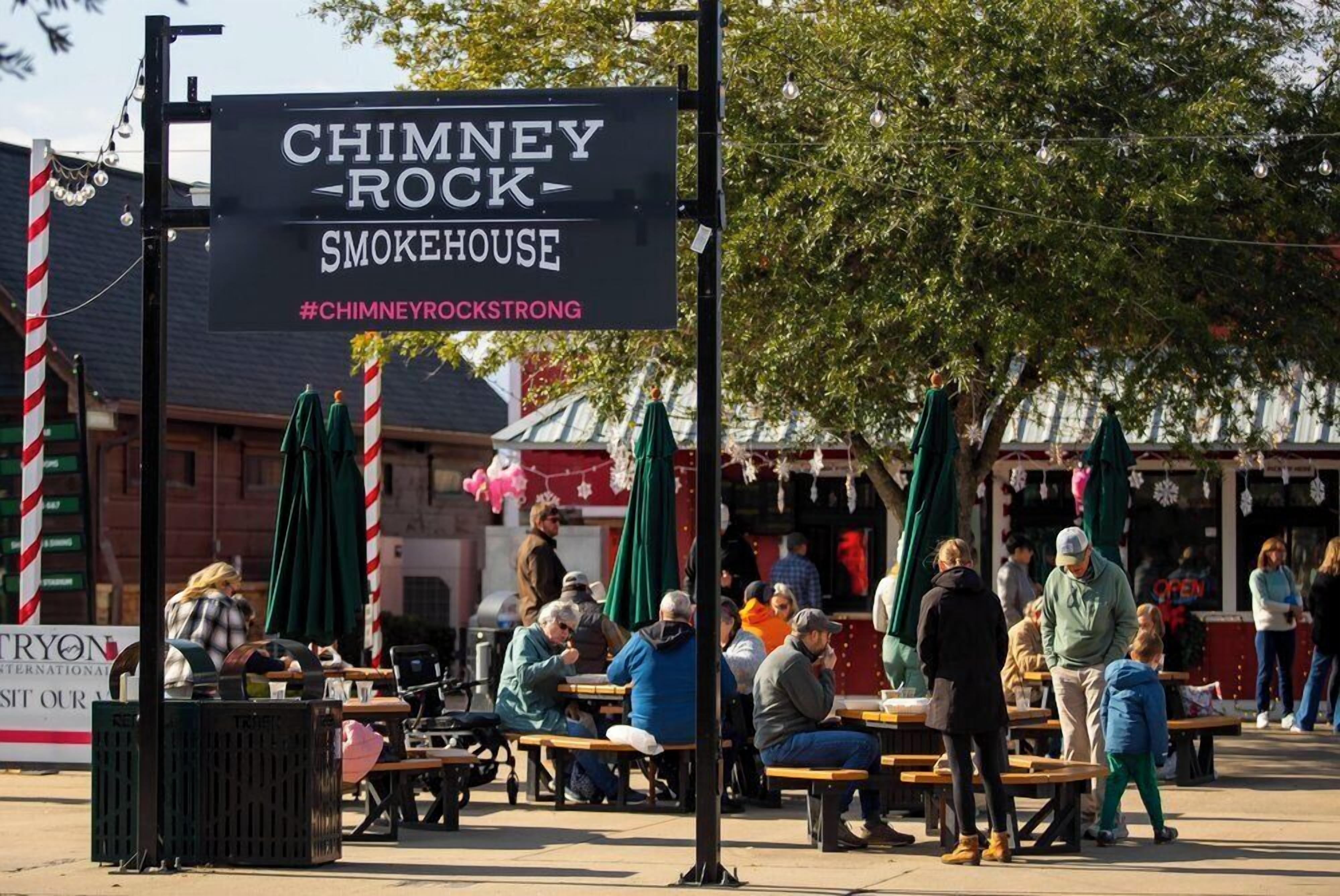 Un área de estar al aire libre con un letrero para Chimney Rock Smokerhouse.