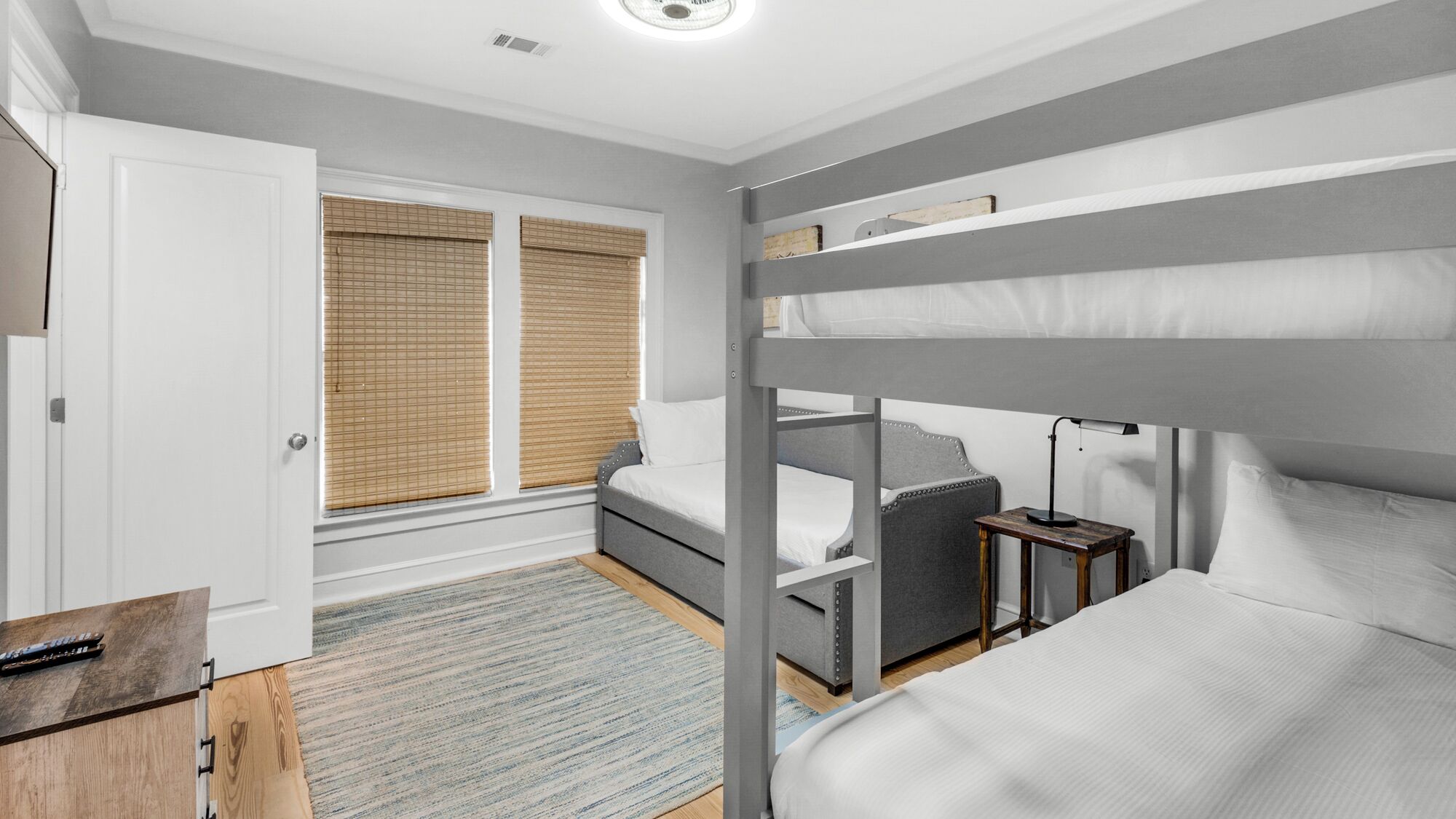 A bedroom with bunk beds, a bedside table, a lamp, and a window with blinds.