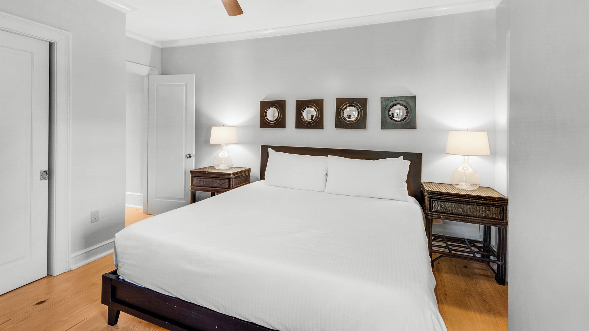 A bedroom with a large bed, two bedside tables with lamps, and a door.