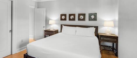 A bedroom with a large bed, two bedside tables with lamps, and a door.
