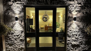 A stone facade with a glass door entrance, a clock, and a well-lit interior with furniture. - Beinn Bhracaigh (Pitlochry)