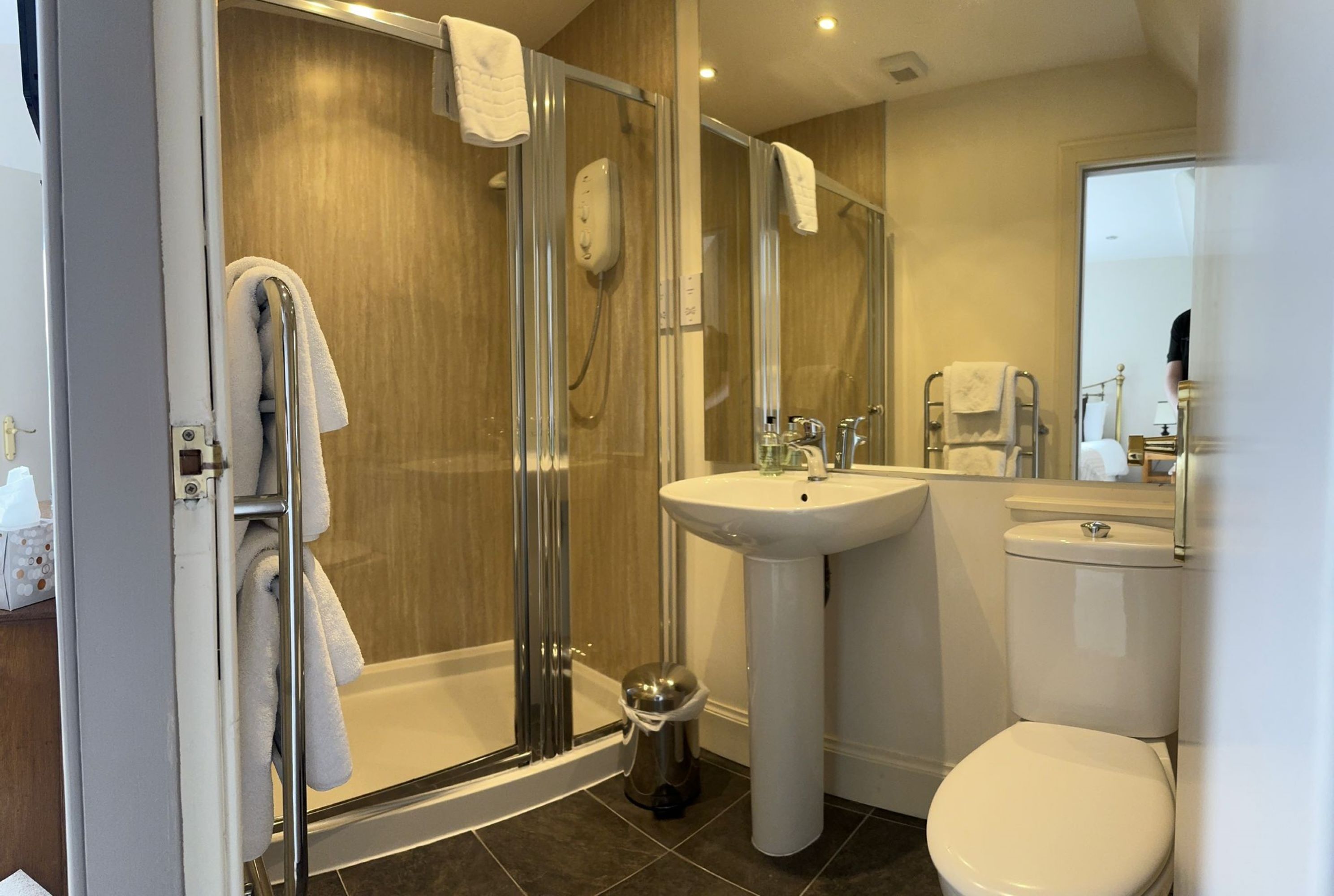 A modern bathroom with a glass-enclosed shower, a pedestal sink, and a toilet.