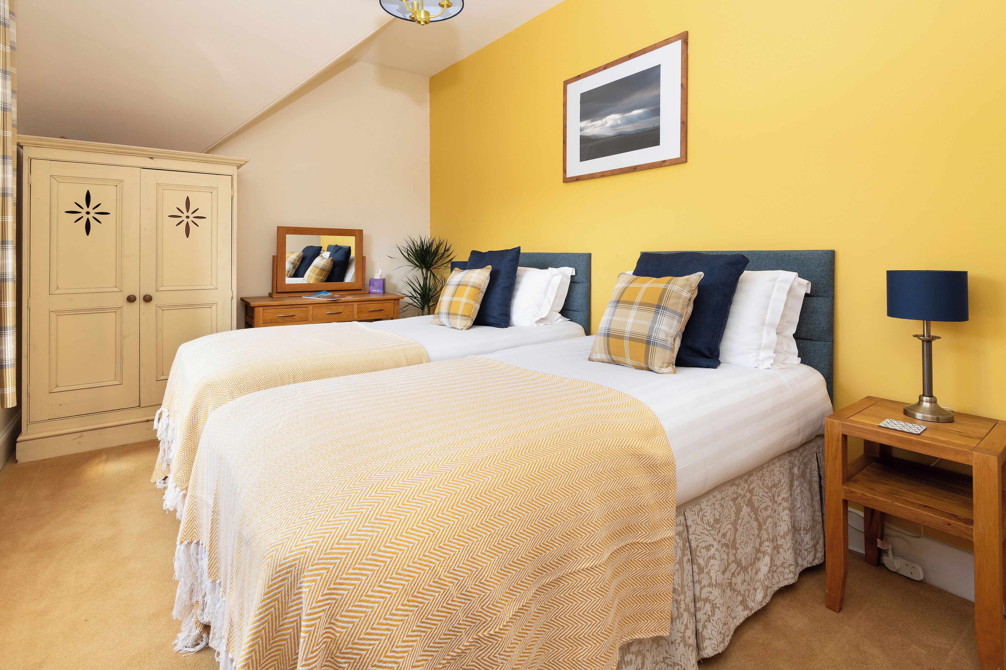 A double bed with two pillows, a bedside table with a lamp, and a wardrobe.