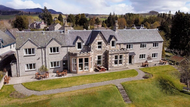 A large stone house with multiple windows, a patio with outdoor furniture, and a well-maintained lawn. - Beinn Bhracaigh (Pitlochry)