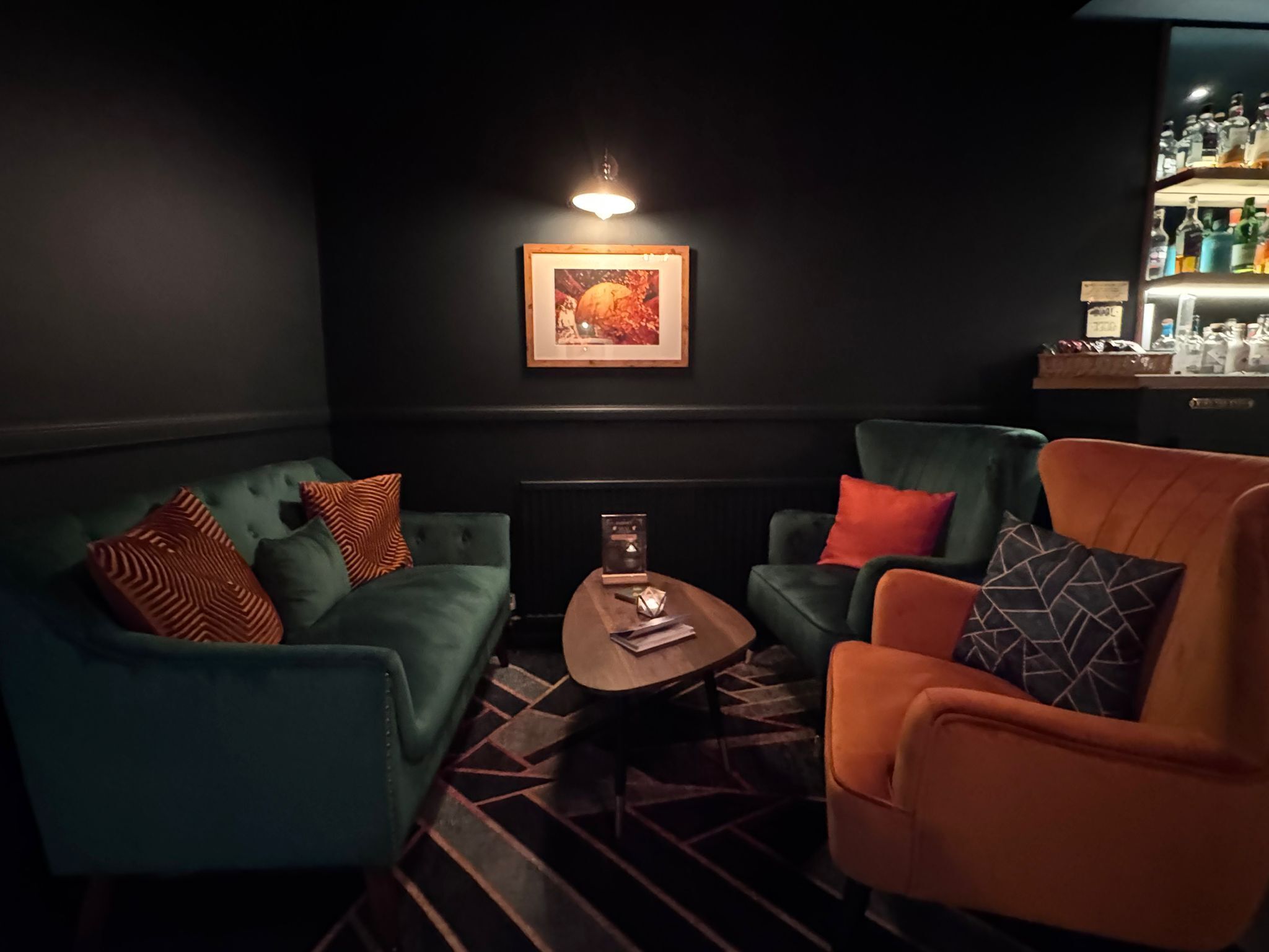 A dark-themed lounge area with a sofa, armchair, and a small table.