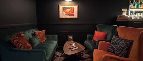 A dark-themed lounge area with a sofa, armchair, and a small table.
