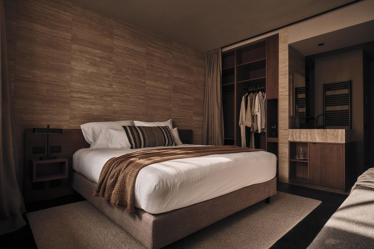 A modern bedroom with a large bed, a wardrobe, and a mirror.
