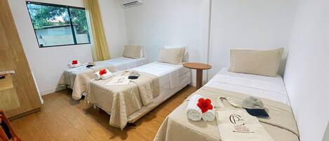 Habitación de hotel con dos camas individuales, una mesita redonda y ventana con vistas al verdor.