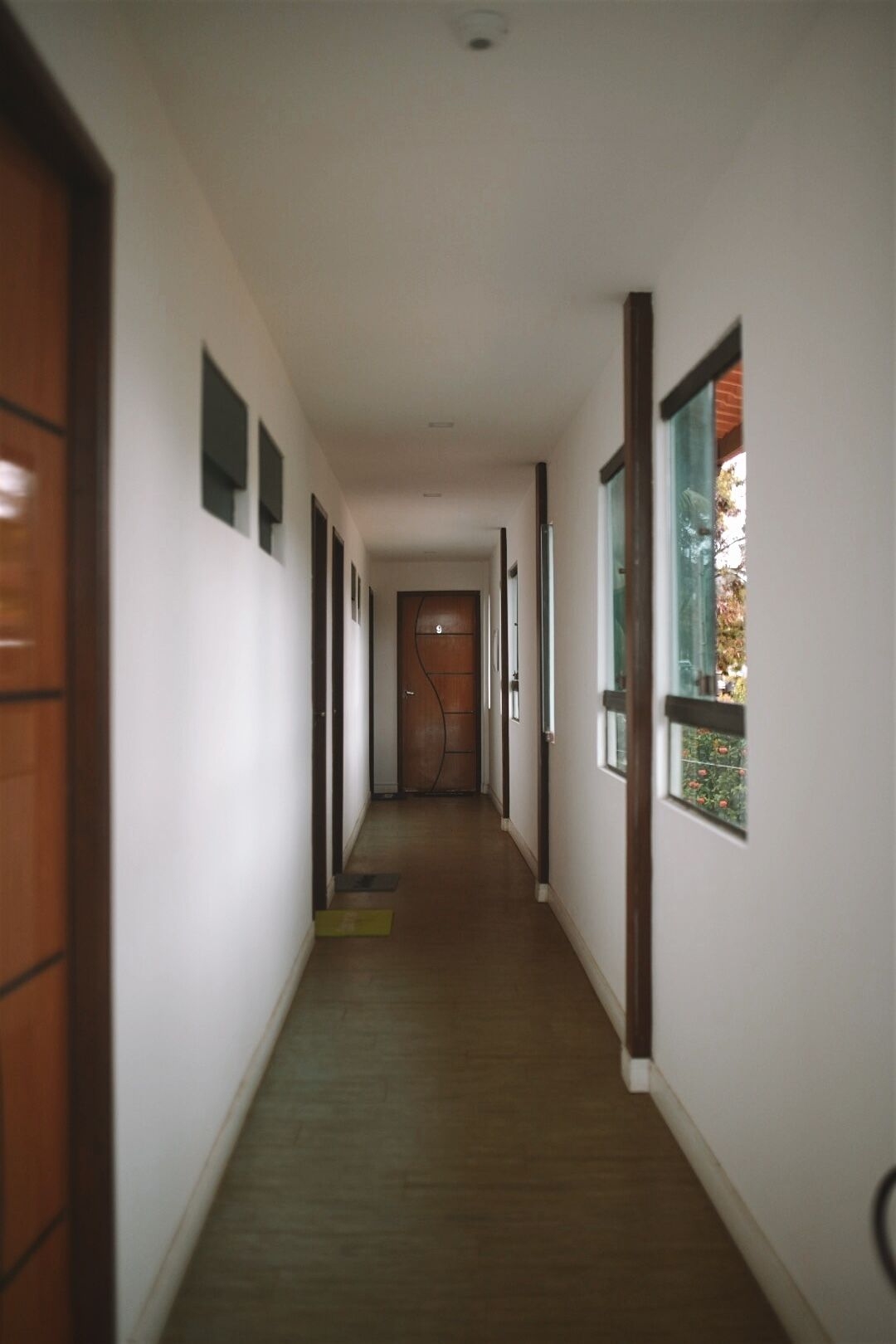 Un long couloir étroit, avec des portes et des fenêtres en bois de part et d’autre.