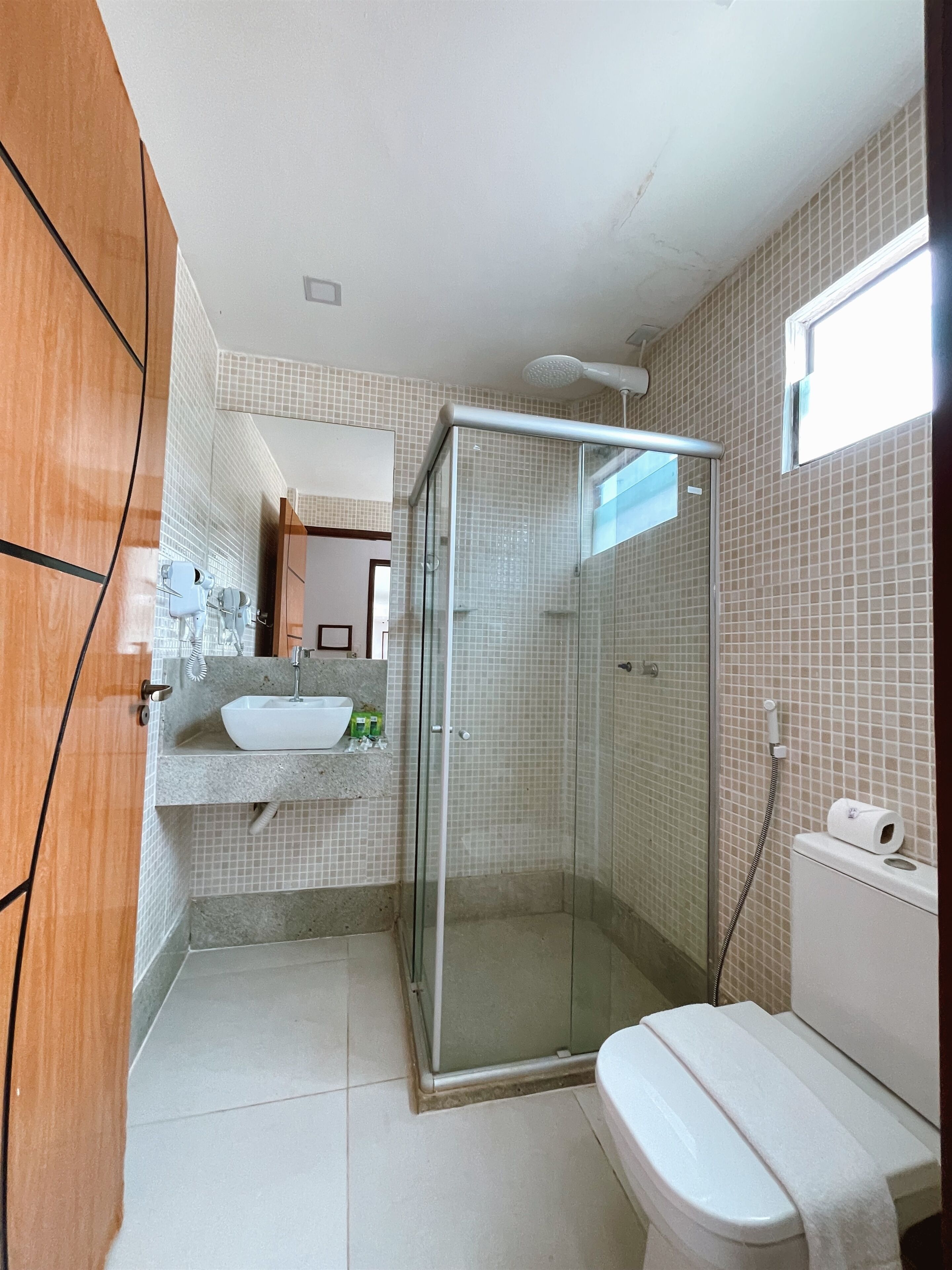 A bathroom with a glass-enclosed shower, a sink with a mirror, and a toilet.