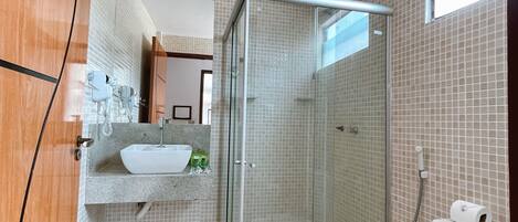 A bathroom with a glass-enclosed shower, a sink with a mirror, and a toilet.