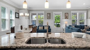 A spacious kitchen with a double sink, pendant lighting, and a view of the outdoors through large windows. - Modern Prominence Home ~ Game Room, 4 Bikes, Sleeps 13, Pet Friendly! (Santa Rosa Beach)