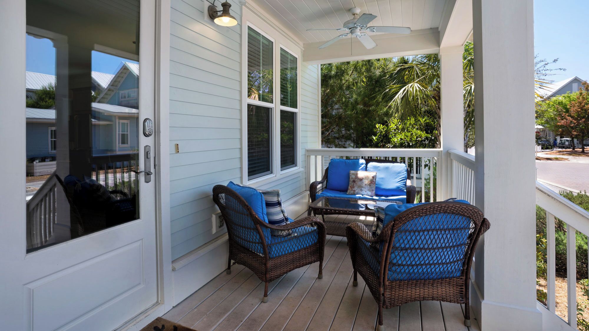 A covered porch with wicker furniture and a glass table.