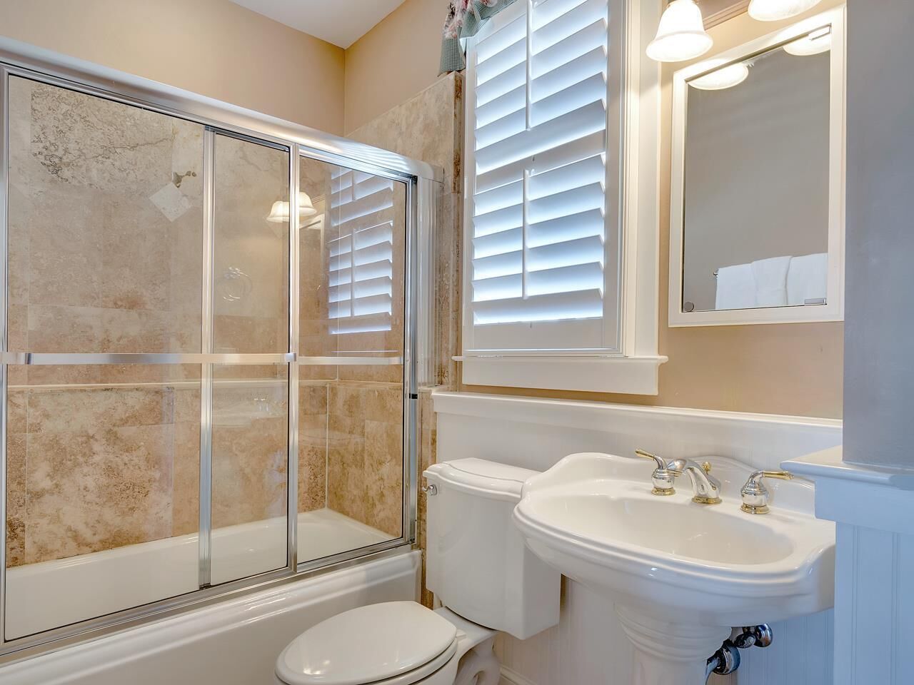 Un baño con ducha de vidrio, inodoro y lavamanos con espejo.