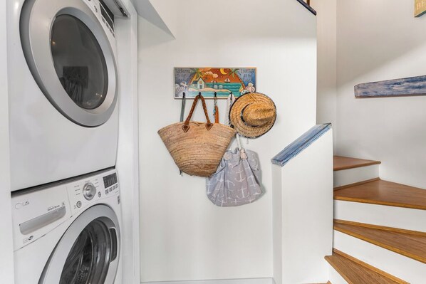 A laundry area with a washing machine and a painting on the wall.