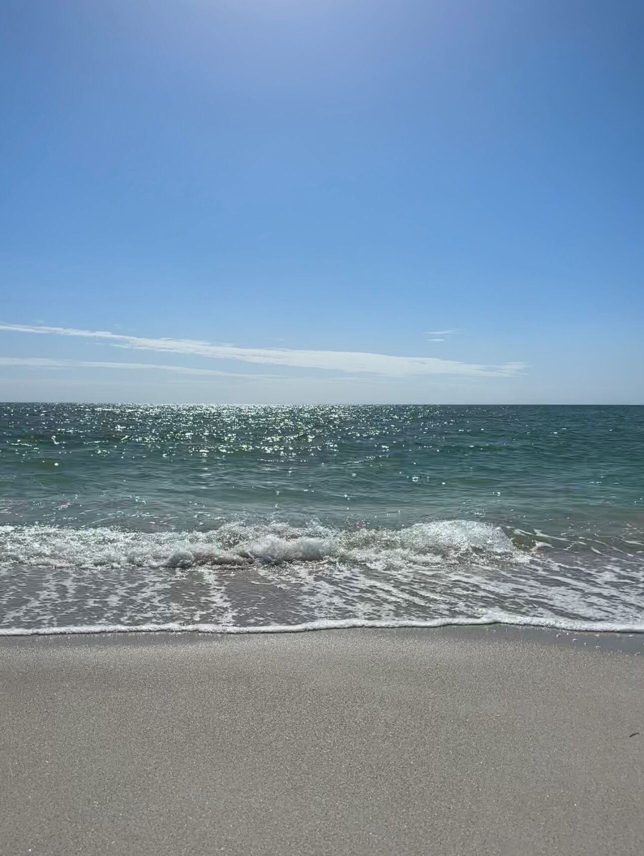 Een strand met heldere lucht en rustige golven.