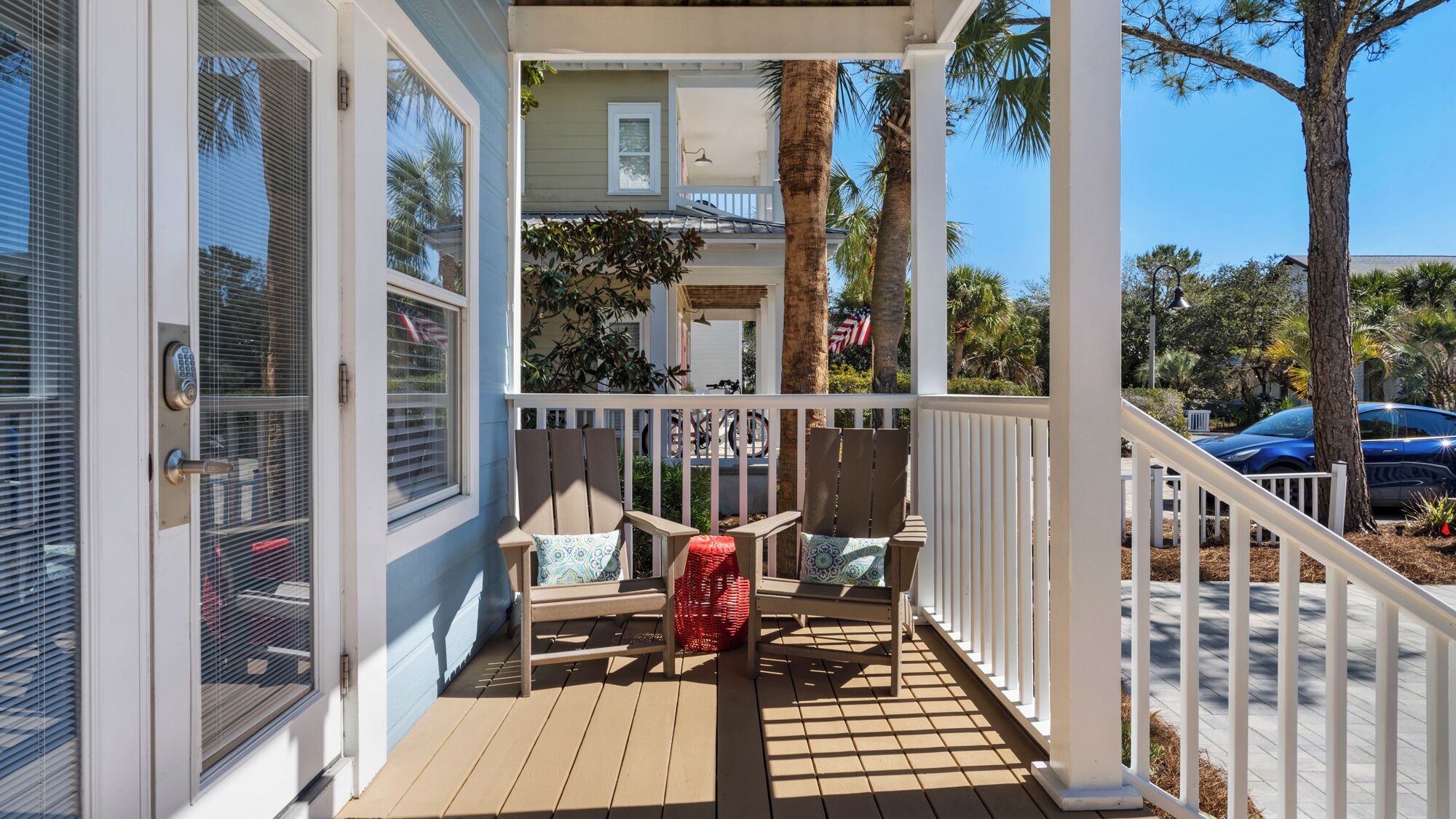 A covered porch with wooden chairs and a red basket.