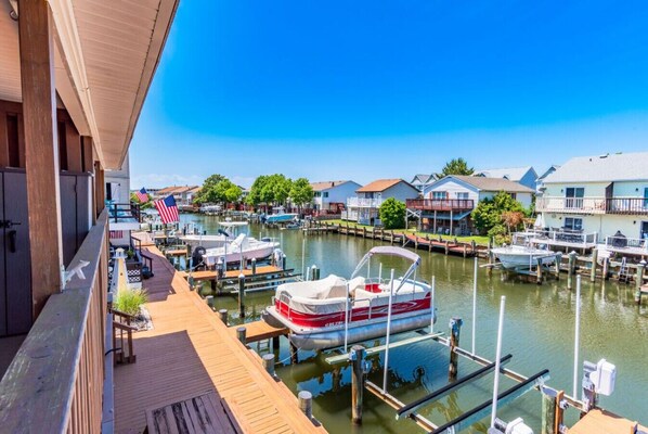 Un port de plaisance avec des bateaux amarrés, des maisons au bord de l’eau et une terrasse en bois.